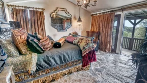 Rustic luxury bedroom at Love of the View in Glen Rose, featuring stone floors and a private balcony for an unplugged weekend getaway.